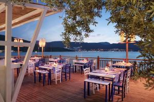 a restaurant with tables and chairs on a deck at DoubleTree by Hilton Bodrum Isil Club Ultra All-Inclusive Resort in Torba