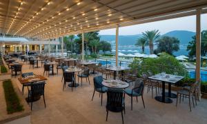 a restaurant with tables and chairs on a patio at DoubleTree by Hilton Bodrum Isil Club Ultra All-Inclusive Resort in Torba
