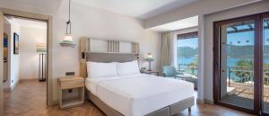 a bedroom with a white bed and a balcony at DoubleTree by Hilton Bodrum Isil Club All-Inclusive Resort in Torba