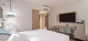 a bedroom with a bed and a desk with a television at DoubleTree by Hilton Bodrum Isil Club Ultra All-Inclusive Resort in Torba