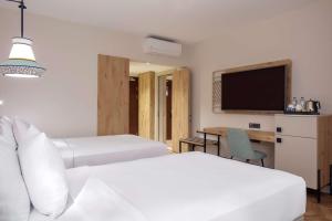 a bedroom with two beds and a desk and a tv at DoubleTree by Hilton Bodrum Isil Club Ultra All-Inclusive Resort in Torba