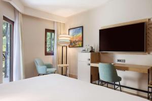a hotel room with a bed and a desk and a tv at DoubleTree by Hilton Bodrum Isil Club Ultra All-Inclusive Resort in Torba