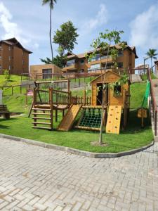 a playground in front of a building with a tree at Eco Resort Praia dos Carneiros - Flat Novo - Ao Lado da Igrejinha in Praia dos Carneiros
