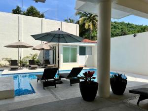 Casa Boutique Maria Bonita في لا مانزايلا: مسبح وكراسي ومظلات بجانب مبنى