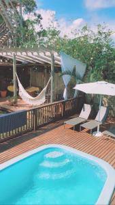 uma piscina num deque de madeira com cadeiras e guarda-sóis em Studios Malakoopa - Praia do Rosa em Praia do Rosa