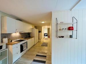 a kitchen with white cabinets and a long hallway at Prestadalen 6 in Sogndal