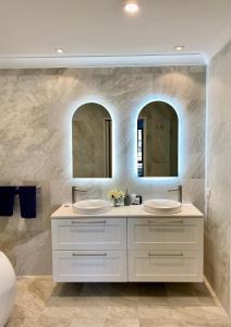a bathroom with two sinks and two mirrors at Ganesha Wellness Spa in Perth
