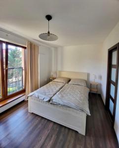 a bedroom with a white bed and a large window at Apartment Gemer & Volovec in Rožňava