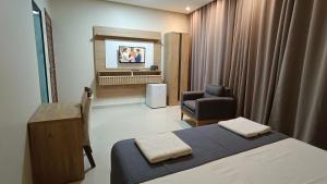 a bedroom with a bed and a chair and a television at Hotel Maxsuel 