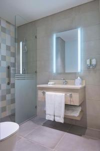a bathroom with a shower and a sink and a mirror at Hampton By Hilton Doha Old Town in Doha