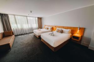 een hotelkamer met 2 bedden en een bank bij Clarion Hotel Townsville in Townsville