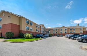 Extended Stay America Suites - Merrillville - US Rte 30 في ميريلفيل: مبنى فيه سيارات متوقفة في موقف للسيارات