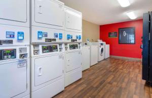 uma lavandaria com máquinas de lavar roupa brancas e uma parede vermelha em Extended Stay America Select Suites - Roanoke - Airport em Roanoke