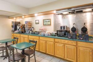 a restaurant with a counter with two tables and chairs at Super 8 by Wyndham Gallipolis Pt Pleasant Area in Gallipolis