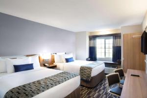 a hotel room with two beds and a desk at Microtel Inn & Suites by Wyndham Vernal/Naples in Vernal +21 photos
