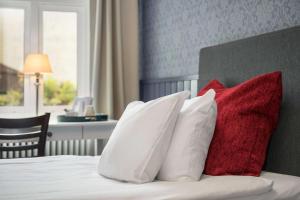 Una cama con cuatro almohadas rojas y blancas. en Hotell Linnéa - Helsingborg en Helsingborg