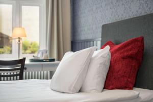 ein Bett mit vier roten und weißen Kissen darauf in der Unterkunft Hotell Linnéa - Helsingborg in Helsingborg