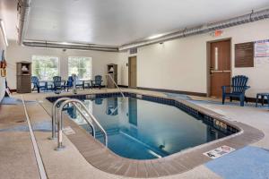 a large swimming pool in a room with chairs and tables at Comfort Inn in Connellsville