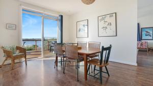 a dining room with a table and chairs and a balcony at 8 Carolynne Street, Merimbula in Merimbula