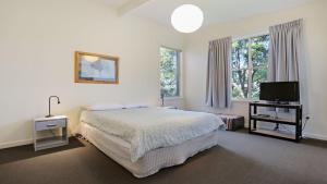 a bedroom with a bed and a tv and windows at 8 Carolynne Street, Merimbula in Merimbula