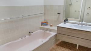 a bathroom with a tub and a sink and a mirror at 8 Carolynne Street, Merimbula in Merimbula +18 photos