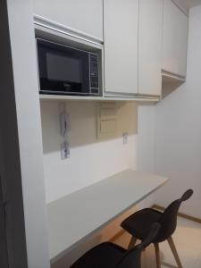 uma cozinha com um micro-ondas e 2 cadeiras pretas em Apartamento Temporada Salvador Pituba em Salvador
