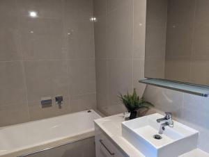 a white bathroom with a sink and a bath tub at Spacious 2 bedroom apartment @Kingston Foreshore in Kingston 