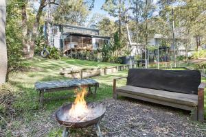 a fire pit with two benches and a couch in a yard at Treescape by the Lake in Murrays Beach