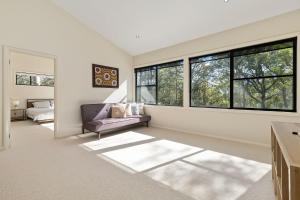 a living room with a couch and windows at Treescape by the Lake in Murrays Beach