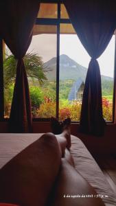 Vista Hermosa Del Arenal في فورتونا: شخص يستلقي على سرير أمام النافذة