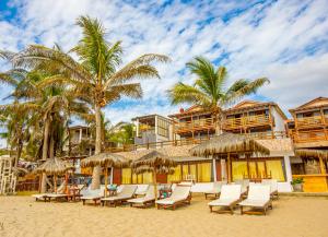 a group of chairs and umbrellas on a beach at Hotel Route 66 in Vichayito