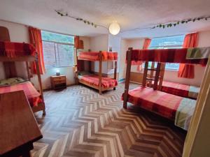 a room with two bunk beds and a table at Hostel Plantas y Blanco in Baños