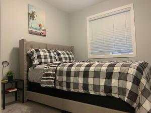 um quarto com uma cama com um cobertor xadrez e uma janela em Luxurious 3 BR Villa with free parking - King Bed em Regina