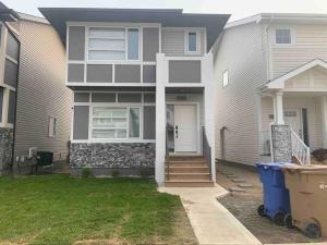 a gray house with a white door and a yard at Luxurious 3 BR Villa with free parking - King Bed in Regina