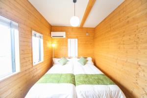 Cama en habitación con paredes y ventanas de madera en Awaji Seaview Resort in Nojima, en Kusumoto