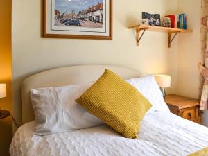 um quarto com uma cama branca e uma almofada amarela em Rowan House em Beverley