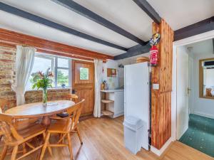 Tarrant Cottage -14557 في West Orchard: مطبخ وغرفة طعام مع طاولة وثلاجة