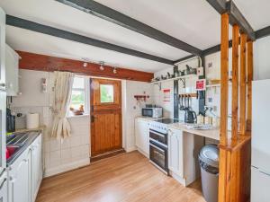 Tarrant Cottage -14557 في West Orchard: مطبخ بأدوات بيضاء وسقف خشبي