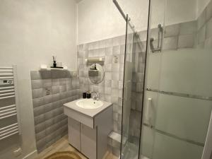 a white bathroom with a sink and a shower at Appartement cosy à Fouras: 1 chambre, proche commerces et plages, Wifi, TV, cuisine équipée - FR-1-709-70 in Fouras