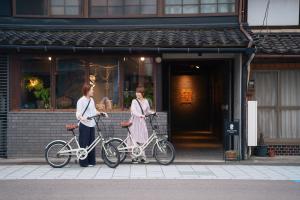 dos mujeres de pie con sus bicicletas delante de una tienda en APARTMENTS by Bed and Craft, en Inami