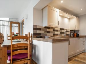 a kitchen with white cabinets and a table and a dining room at Lawn Lodge in Brockenhurst