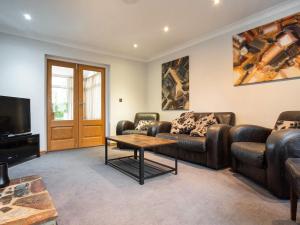 a living room with leather couches and a tv at Lawn Lodge in Brockenhurst