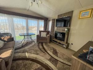 a living room with a couch and a table and a television at Lovely Caravan With Decking At North Denes Park In Suffolk, Ref 40050nd in Lowestoft