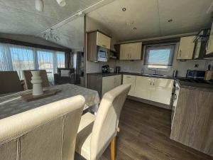 a kitchen with white cabinets and a table and chairs at Lovely Caravan With Decking At North Denes Park In Suffolk, Ref 40050nd in Lowestoft