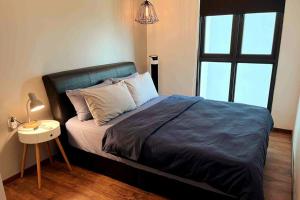 1 dormitorio con 1 cama grande, mesita de noche y lámpara en Home Abroad 2 @ Jazz Suites Vivacity, en Kuching