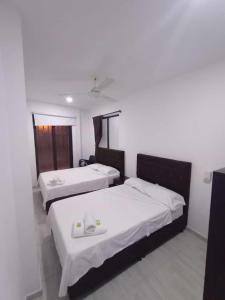 a room with three beds with white sheets and a window at ONE HOTEL in Girardot