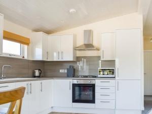 a kitchen with white cabinets and a stove top oven at Lodge 38 in Stonham Aspall