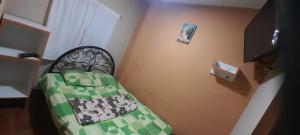 a small bedroom with a bed with a green comforter at Hospedaje In House in La Merced