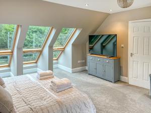 a bedroom with a bed and a flat screen tv at Whydown Cottage in Hooe