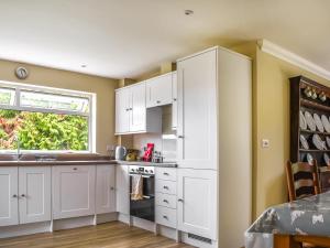 una cocina con armarios blancos y una ventana en An Croke en Higham